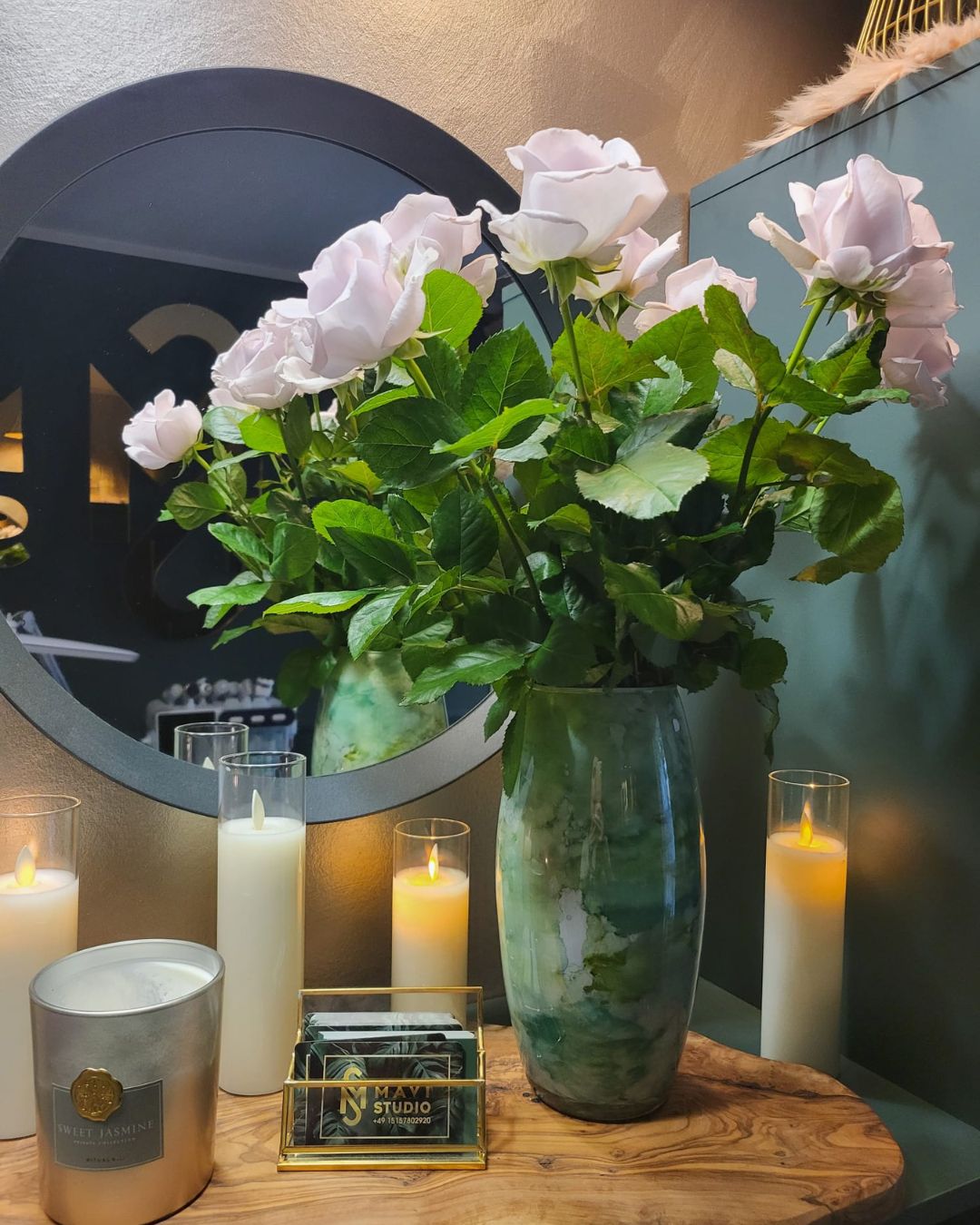 Ein Strauß rosa Blumen in einer Vase und brennende Kerzen.